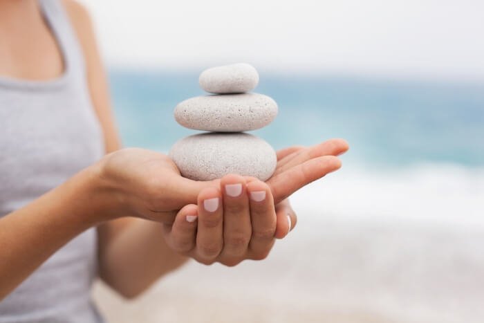 Femme tenant des pierres dans ses mains : naturopathie, massage, yoga à Ingré